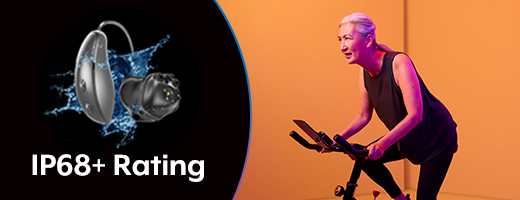 Woman sweating on exercise bike wearing Starkey hearing aids